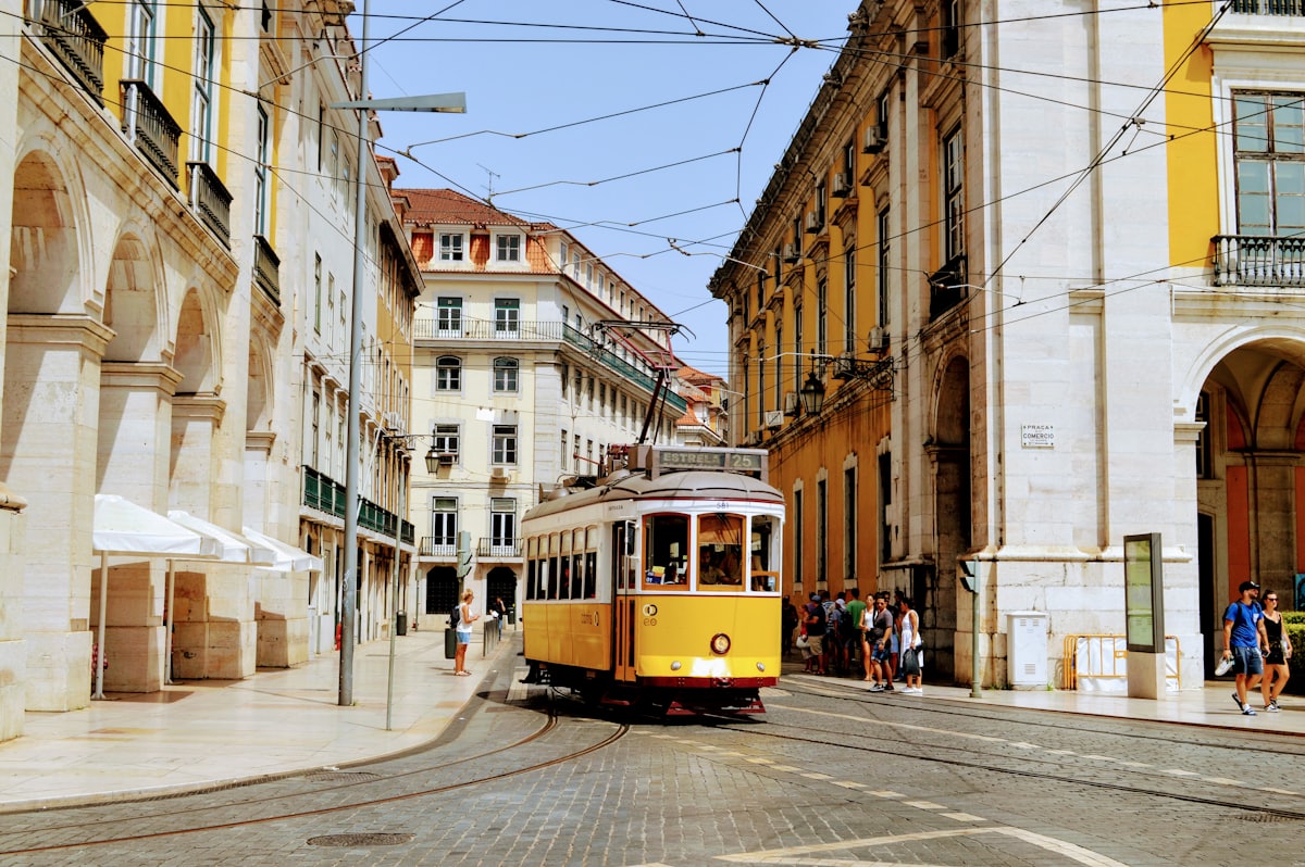A yellow tram climbing a historic street in Lisbon, Portugal