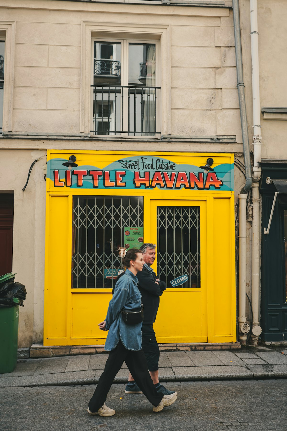 Pedestrians passing a bright yellow Little Havana restaurant